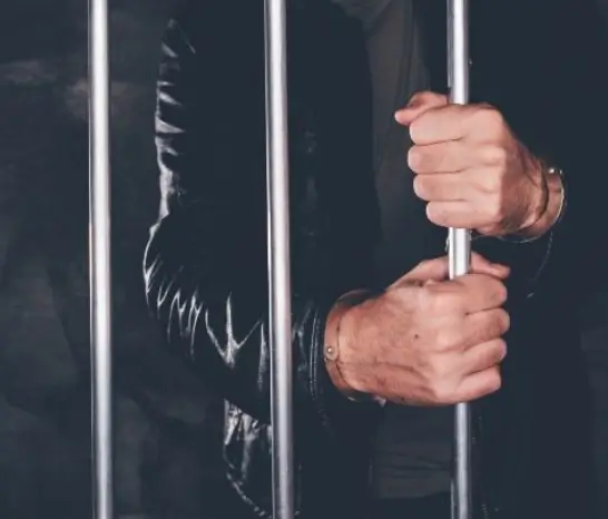 A men inside jail holding bars after commiting crime.